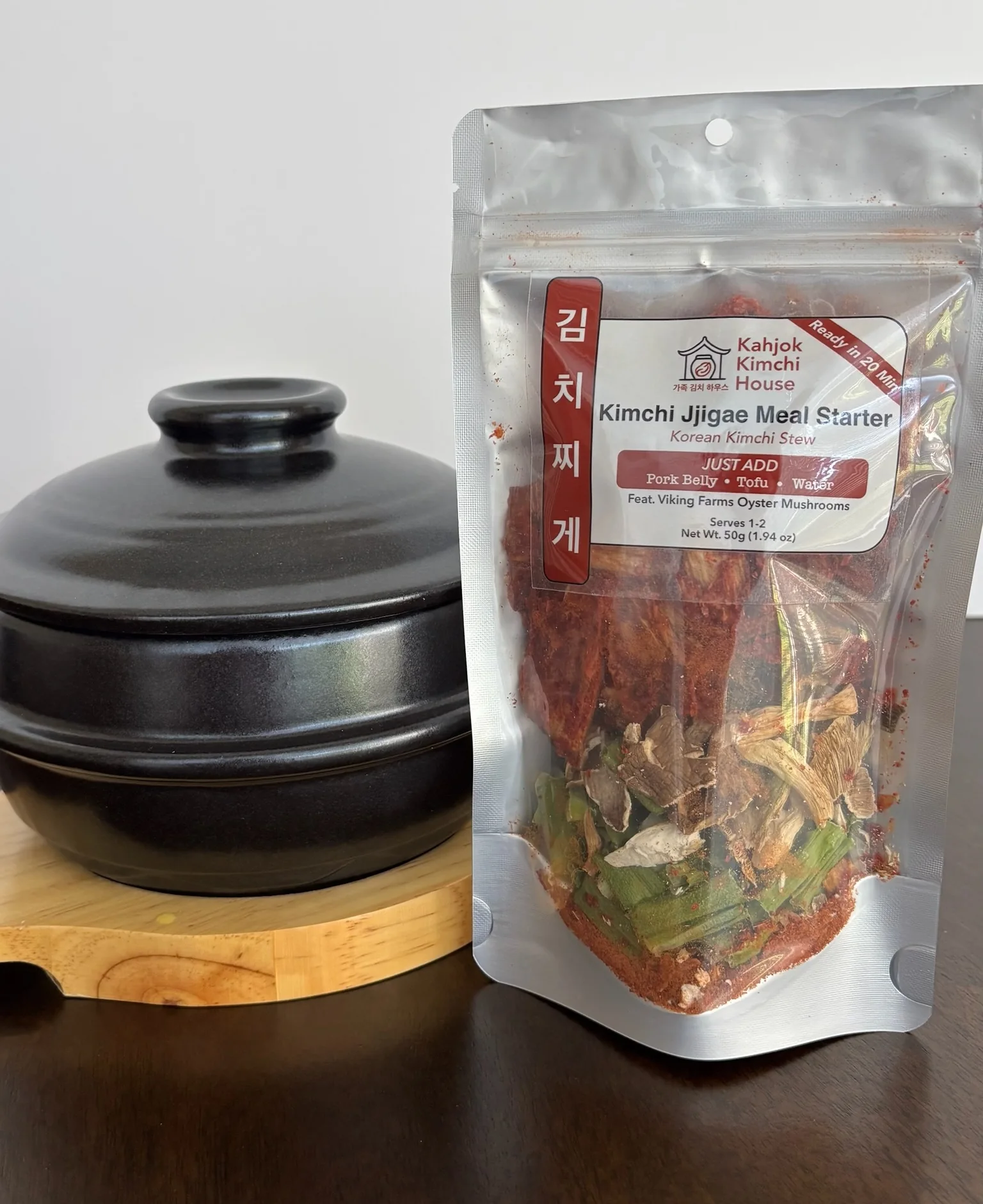 Kahjok Kimchi House Kimchi Jjigae Meal Starter beside a traditional black stew bowl