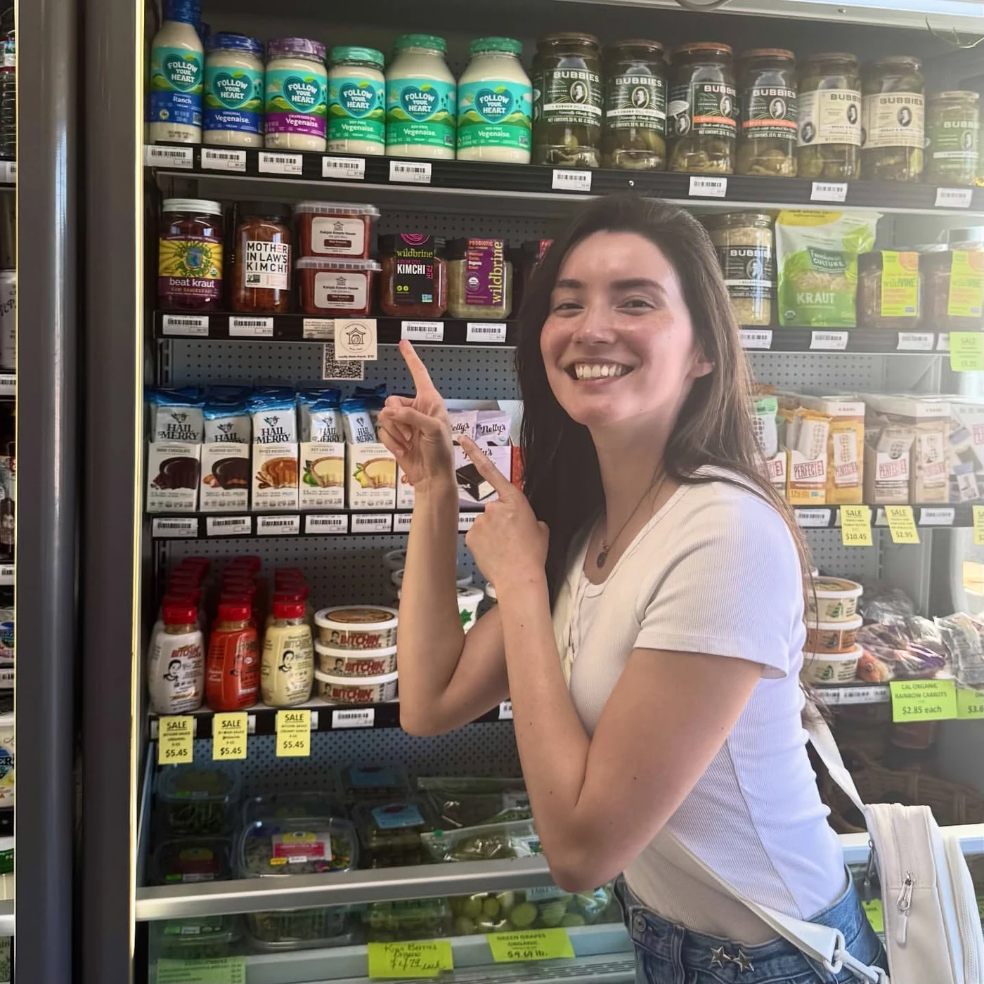 Fiona Daub pointing to Kahjok Kimchi House kimchi on the shelf at Village Foods & Pharmacy in Bryan, Texas