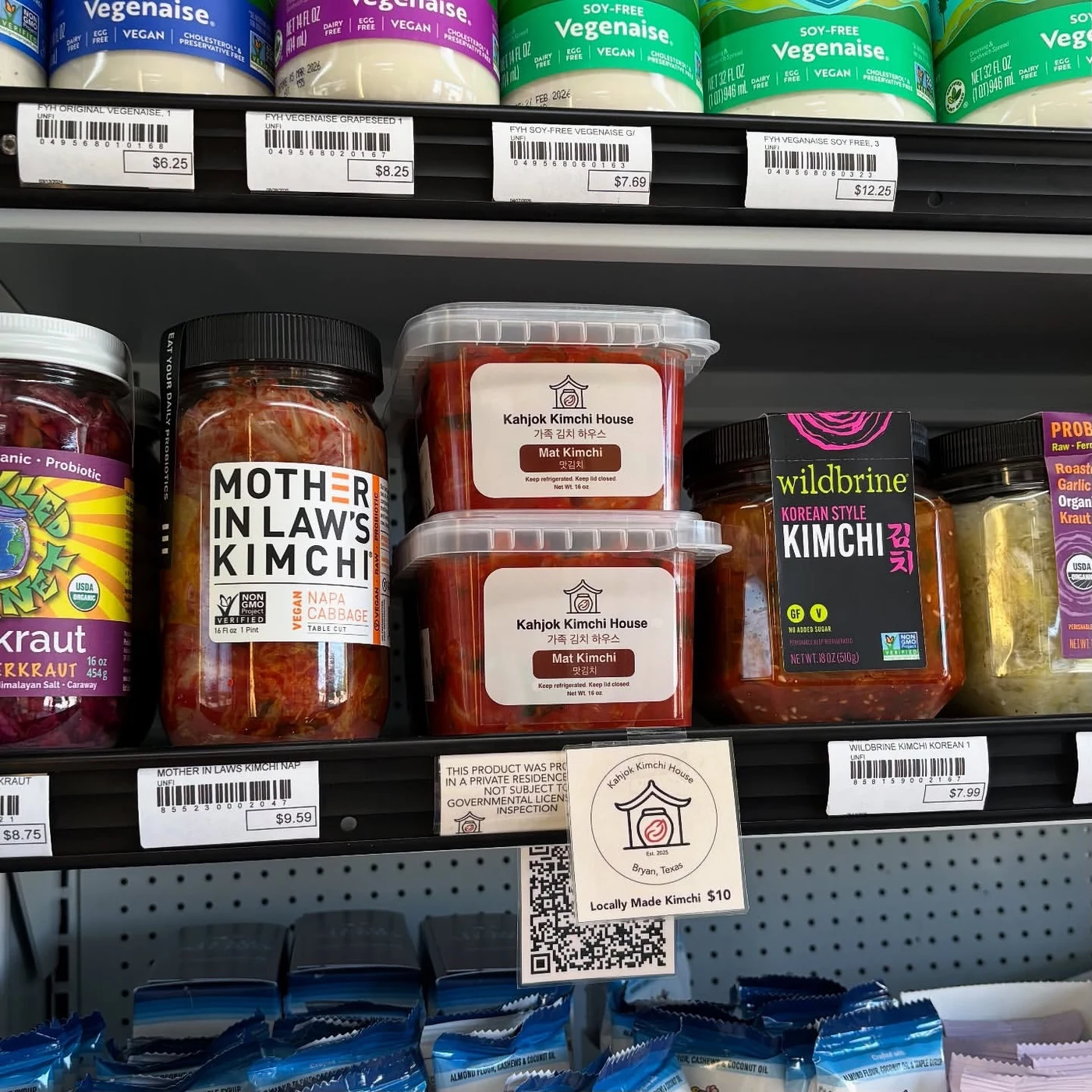 Jars of kimchi with two stacked jars of Kahjok Kimchi House mat kimchi at the center